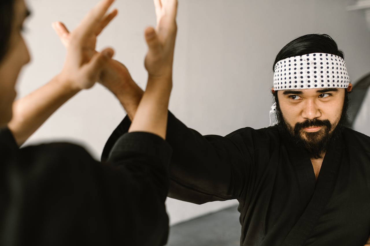 Bearded martial artist practicing self-defense with focus and precision indoors.